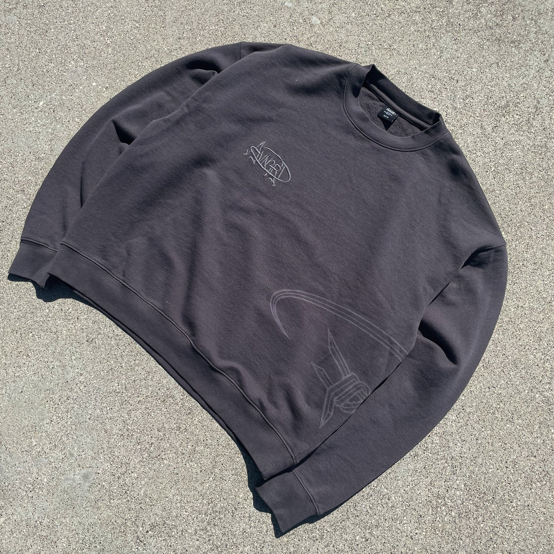 a zoom of a detailed crewneck with graffiti graphics, laser print and emboidery on the front